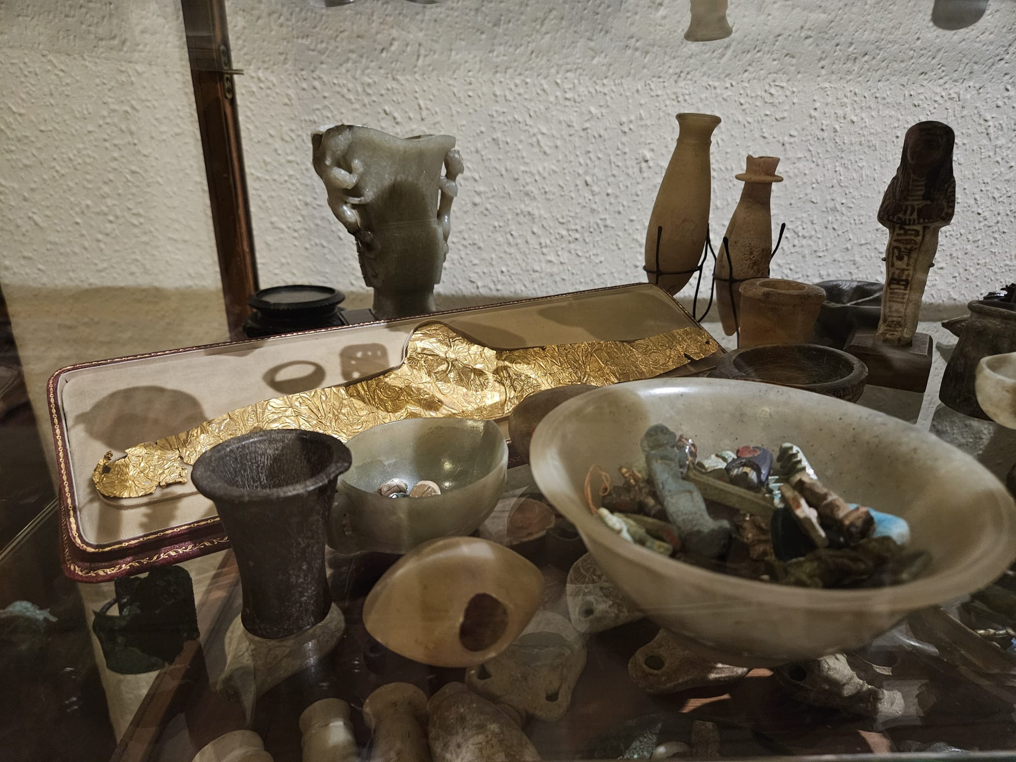 Yellow and purple image of a collection of antiquities for sale, including ancient Greek and Ancient Roman vases, gold, and pottery for sale by an antiquities dealer